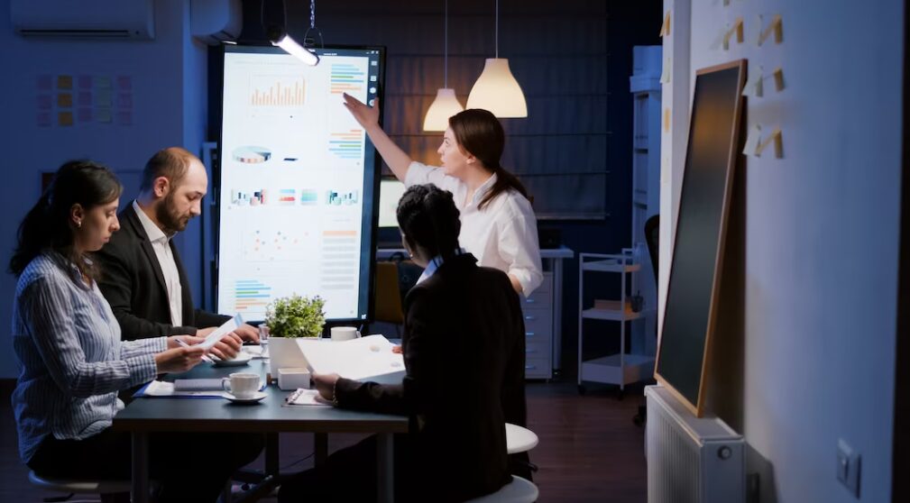 Business team brainstorming around a table with 'Creating Effective Company Objectives' written on a whiteboard, exemplifying strategic planning.